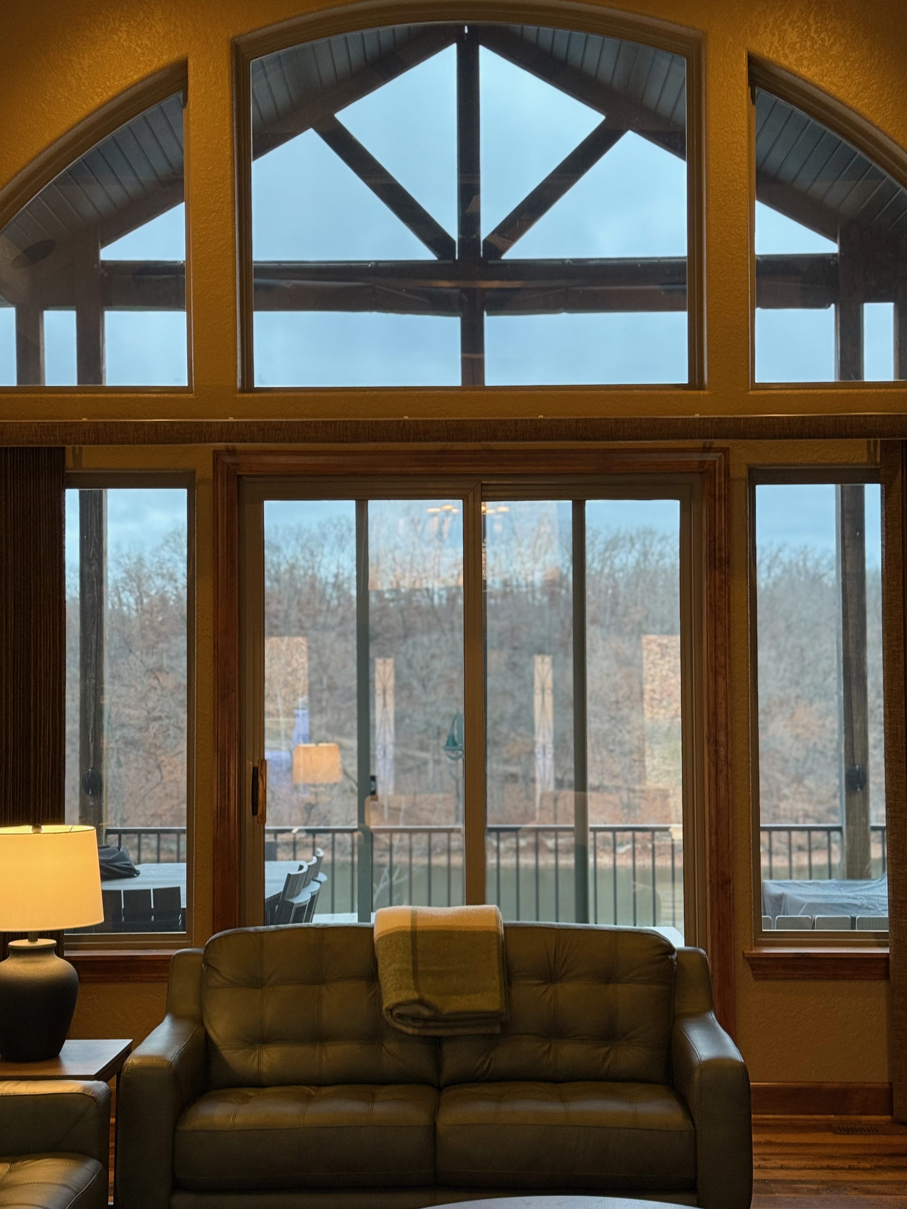 Vaulted arched windows with lake view and green leather sofa
